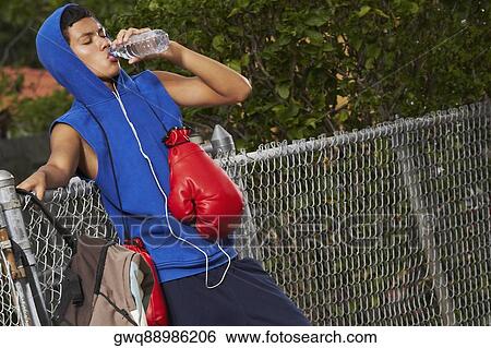 Side profile of a teenage boy listening an ipod and drinking water from a bottle View Large Photo Image Stock Photograph - Side profile of a teenage boy listening an ipod and drinking water from a bottle. Fotosearch