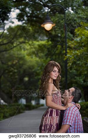 Side profile of a young couple romancing View Large Photo Image Stock Photograph - Side profile of a young couple romancing. Fotosearch