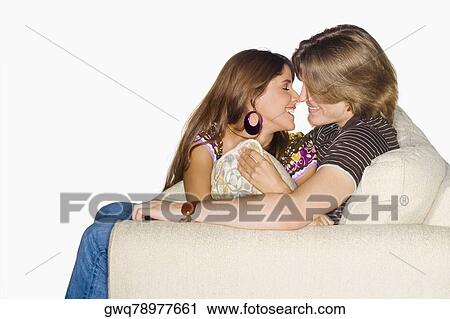 Side profile of a young couple sitting on a couch and nuzzling View Large Photo Image Stock Image - Side profile of a young couple sitting on a couch and nuzzling. Fotosearch