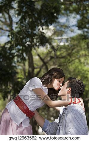 Side profile of a young couple romancing in a park View Large Photo Image Stock Image - Side profile of a young couple romancing in a park. Fotosearch