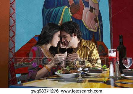 Side profile of a young couple toasting wine in a restaurant View Large Photo Image Stock Photograph - Side profile of a young couple toasting wine in a restaurant. Fotosearch