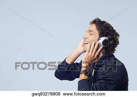 Side profile of a young man listening to music and smiling View Large Photo Image Stock Photo - Side profile of a young man listening to music and smiling. Fotosearch