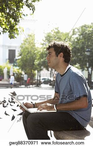 Side profile of a young man using a laptop View Large Photo Image Stock Image - Side profile of a young man using a laptop. Fotosearch