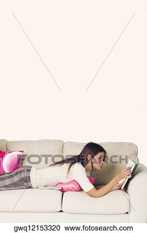 Side profile of a young woman lying on a couch and reading a book View Large Photo Image Stock Image - Side profile of a young woman lying on a couch and reading a book. Fotosearch