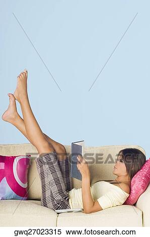 Side profile of a young woman lying on a couch and reading a book View Large Photo Image Stock Photography - Side profile of a young woman lying on a couch and reading a book. Fotosearch