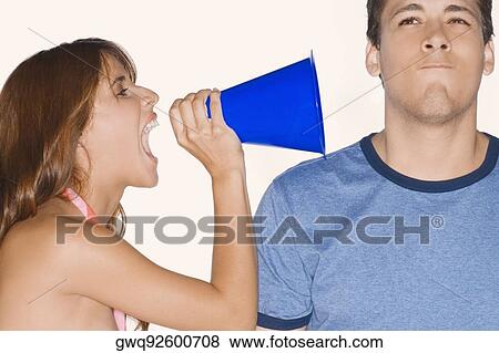 Side profile of a young woman shouting with a megaphone into a young man's ear View Large Photo Image Stock Photo - Side profile of a young woman shouting with a megaphone into a young man's ear. Fotosearch