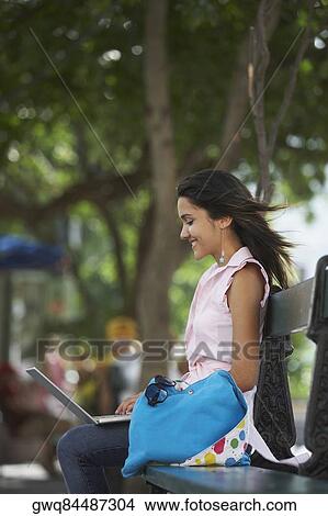 Picture - Side profile of a young woman sitting in a park and using a laptop, Old San Juan, San Juan, Puerto Rico. Fotosearch