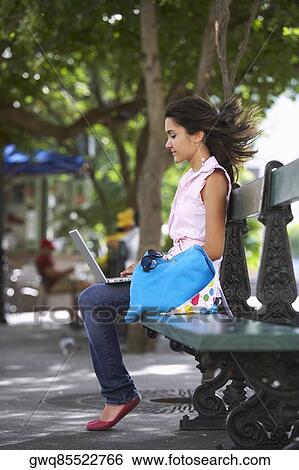 Side profile of a young woman sitting in a park and using a laptop, Old San Juan, San Juan, Puerto Rico View Large Photo Image Stock Photograph - Side profile of a young woman sitting in a park and using a laptop, Old San Juan, San Juan, Puerto Rico. Fotosearch