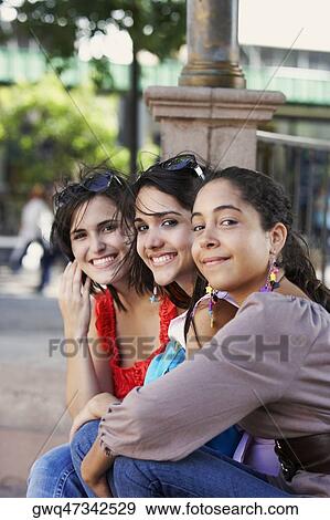 Stock Photo - Side profile of three young women sitting together and smiling, Old San Juan, San Juan, Puerto Rico. Fotosearch