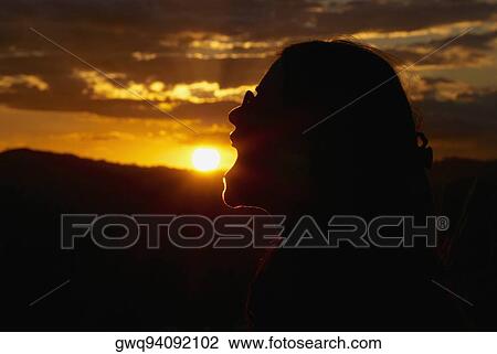 Silhouette of a woman pretending to eat sun at dusk View Large Photo Image Stock Image - Silhouette of a woman pretending to eat sun at dusk. Fotosearch