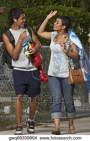Picture - Teenage boy and his sister looking at each other and walking on the walkway. Fotosearch
