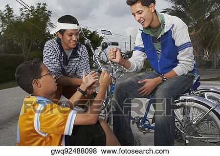 Teenage boy gesturing to his two friends and smiling View Large Photo Image Stock Photo - Teenage boy gesturing to his two friends and smiling. Fotosearch