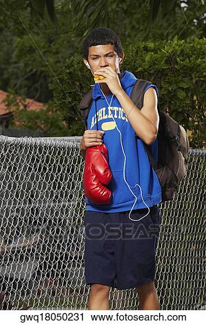 Teenage boy listening an ipod and eating empanada View Large Photo Image Stock Image - Teenage boy listening an ipod and eating empanada. Fotosearch