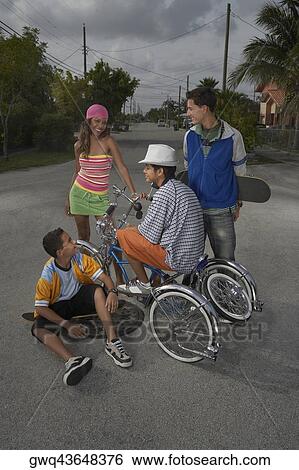 Stock Photograph - Teenage boy on a low rider bicycle with his three friends beside him. Fotosearch