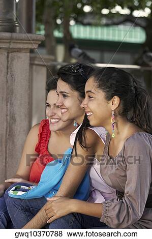 Three young women sitting together and smiling View Large Photo Image Stock Photo - Three young women sitting together and smiling. Fotosearch