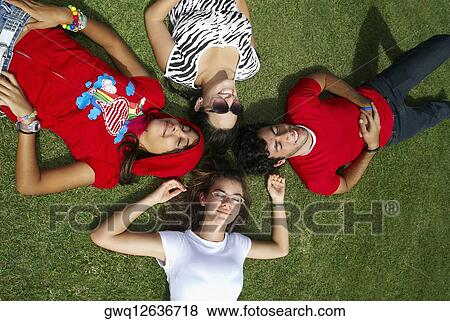 Three young women with a young man lying on grass and smiling View Large Photo Image Stock Photo - Three young women with a young man lying on grass and smiling. Fotosearch
