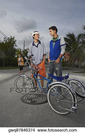 Two teenage boys standing behind a low rider bicycle View Large Photo Image Picture - Two teenage boys standing behind a low rider bicycle. Fotosearch