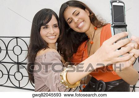 Two young women taking a photograph of themselves View Large Photo Image Stock Image - Two young women taking a photograph of themselves. Fotosearch