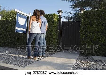 Young couple looking at realty sign near fence View Large Photo Image Stock Photo - Young couple looking at realty sign near fence. Fotosearch