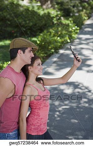 Young couple taking a photograph of themselves with a mobile phone View Large Photo Image Picture - Young couple taking a photograph of themselves with a mobile phone. Fotosearch