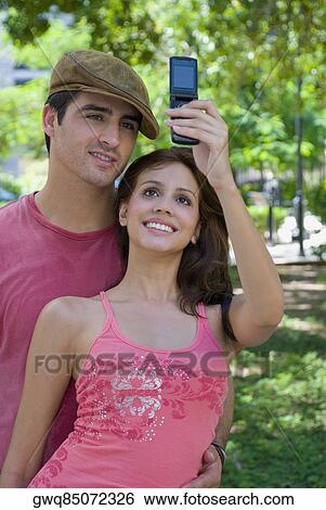 Stock Photograph - Young couple taking a photograph of themselves with a mobile phone. Fotosearch