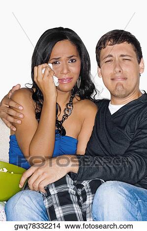 Young man and a teenage girl watching television and crying View Large Photo Image Picture - Young man and a teenage girl watching television and crying. Fotosearch