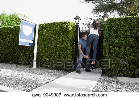 Young man boosting young woman over fence View Large Photo Image Stock Photo - Young man boosting young woman over fence. Fotosearch