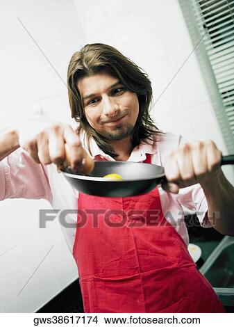 Young man breaking eggs on a frying pan View Large Photo Image Picture - Young man breaking eggs on a frying pan. Fotosearch