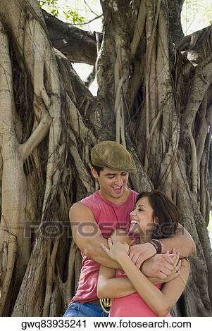 Young man embracing a young woman from behind and smiling View Large Photo Image Stock Image - Young man embracing a young woman from behind and smiling. Fotosearch