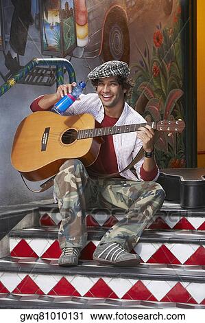 Young man playing a guitar and holding a water bottle View Large Photo Image Stock Image - Young man playing a guitar and holding a water bottle. Fotosearch