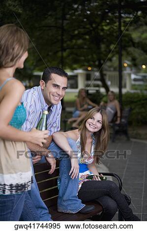 Young man sitting between two young women and smiling View Large Photo Image Stock Photography - Young man sitting between two young women and smiling. Fotosearch
