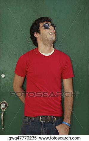Stock Photography - Young man standing in front of a closed door and wearing sunglasses. Fotosearch