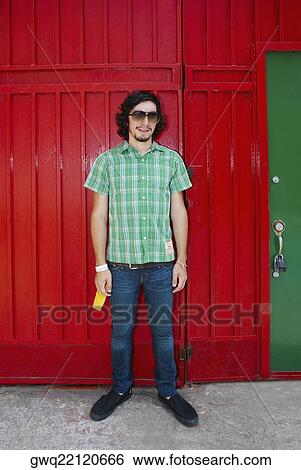 Young man standing in front of a gate View Large Photo Image Stock Photograph - Young man standing in front of a gate. Fotosearch