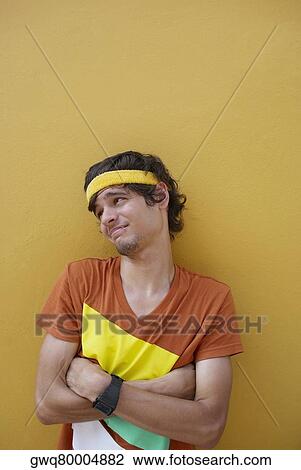 Young man standing with his arms crossed and making a face View Large Photo Image Stock Image - Young man standing with his arms crossed and making a face. Fotosearch