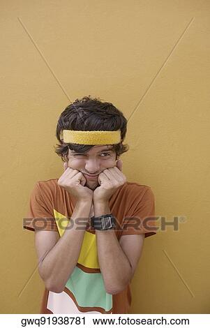 Young man standing with his hands on his chin and making a face View Large Photo Image Stock Image - Young man standing with his hands on his chin and making a face. Fotosearch