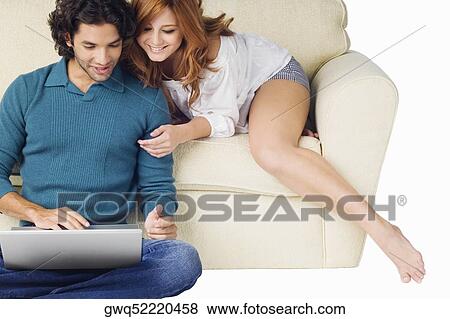 Young man using a laptop with a young woman leaning over him View Large Photo Image Stock Photo - Young man using a laptop with a young woman leaning over him. Fotosearch