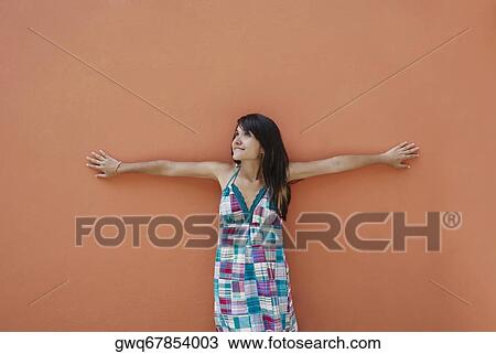 Stock Image - Young woman leaning against a wall. Fotosearch