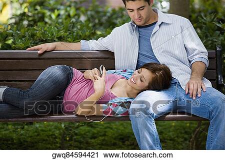 Young woman lying on the lap of a young man and listening to music View Large Photo Image Stock Image - Young woman lying on the lap of a young man and listening to music. Fotosearch