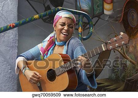 Young woman playing a guitar and singing View Large Photo Image Stock Photo - Young woman playing a guitar and singing. Fotosearch