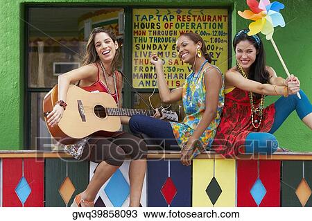 Young woman playing a guitar with her two friends holding a pinwheel and an ipod View Large Photo Image Stock Image - Young woman playing a guitar with her two friends holding a pinwheel and an ipod. Fotosearch