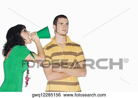 Young woman shouting with a megaphone into a young man's ear View Large Photo Image Stock Photograph - Young woman shouting with a megaphone into a young man's ear. Fotosearch