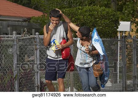 Stock Photograph - Young woman walking beside his brother and touching his head. Fotosearch