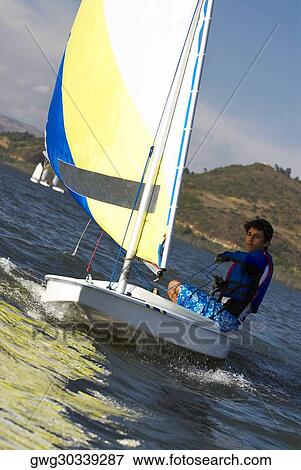 Boy participating in a sailboat race View Large Photo Image Stock Photo - Boy participating in a sailboat race. Fotosearch
