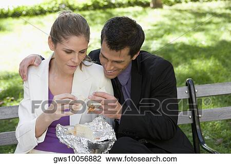 Businessman and a businesswoman having food on a park bench View Large Photo Image Stock Image - Businessman and a businesswoman having food on a park bench. Fotosearch