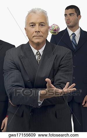 Stock Photo - Businessman catching a rubber band ball with two businessmen standing behind him. Fotosearch