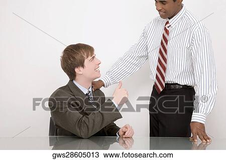Stock Image - Businessman showing thumbs up sign to another businessman. Fotosearch