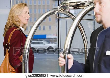 Stock Image - Businesswoman and a porter standing at the entrance of a hotel. Fotosearch