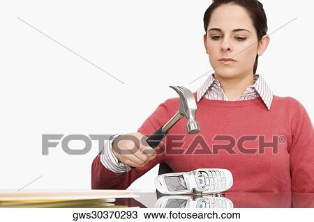 Stock Image - Businesswoman breaking a mobile phone with a hammer. Fotosearch