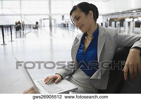 Businesswoman sitting at an airport and using a laptop View Large Photo Image Stock Image - Businesswoman sitting at an airport and using a laptop. Fotosearch