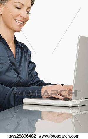 Businesswoman working on a laptop and smiling View Large Photo Image Stock Image - Businesswoman working on a laptop and smiling. Fotosearch